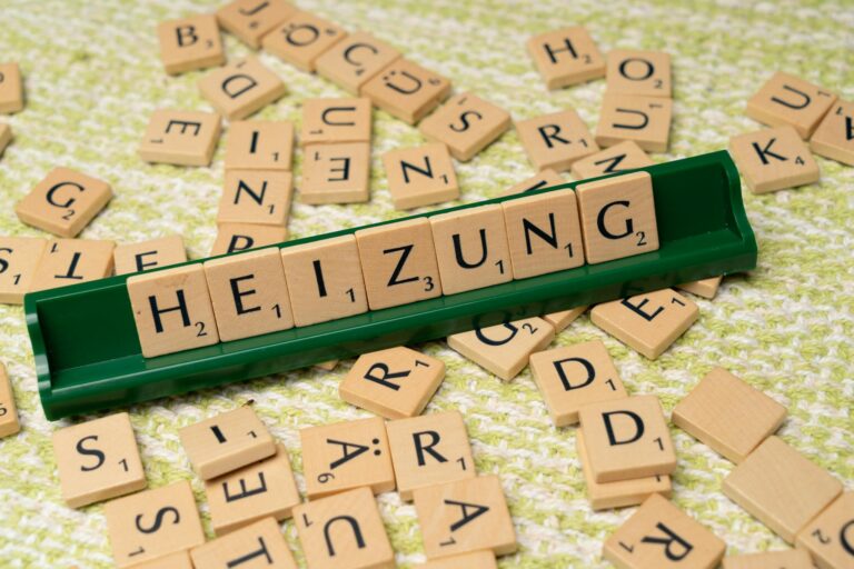 Close-up of wooden Scrabble tiles forming the word 'HEIZUNG' on a textured surface.